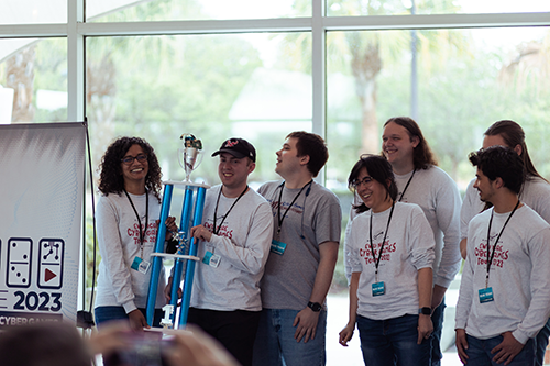 Winners of the 2023 Cyber Games Competition, holding up a large trophy.